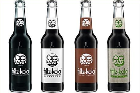 Vier Flaschen Fritz-Kola in Schwarz, Weiß, Braun und Grün, jede mit einem zweigesichtigen Logo und Markennamen.