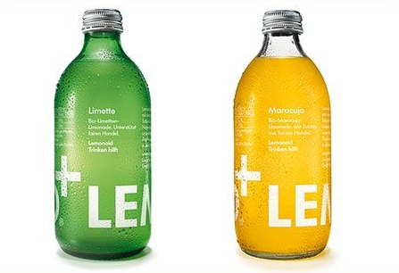 Zwei Glasflaschen Limonade: eine grüne „Limetto“, eine gelbe „Marmoso“ mit weißen Etiketten und silbernen Verschlüssen.