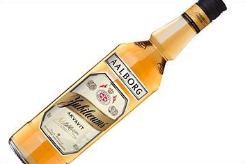 Flasche Aalborg Jubilæums Akvavit, blass bernsteinfarbene Flüssigkeit, weißes Etikett, schwarzer Verschluss, schräg auf Weiß.