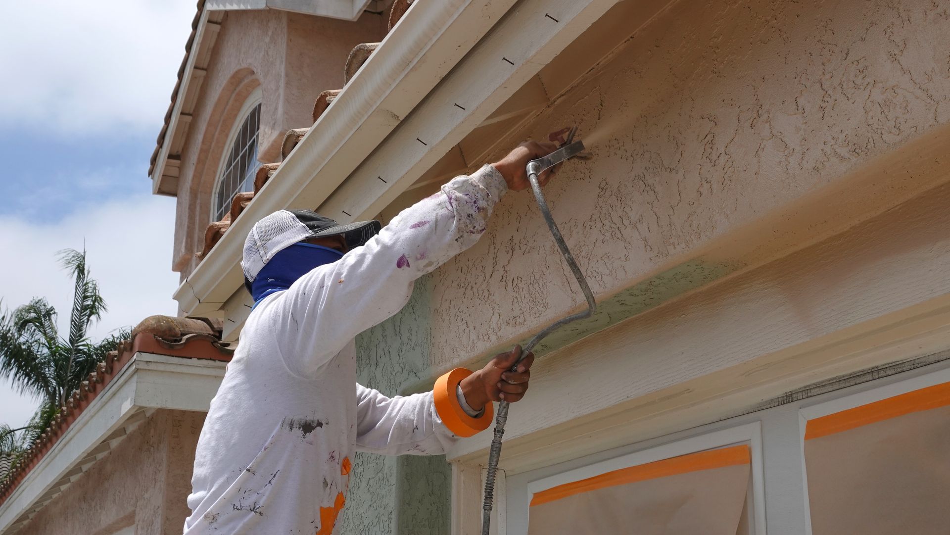 Un façadier qui applique de la peinture sur une façade