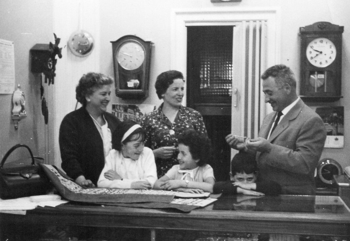 Un grupo de personas de pie alrededor de una mesa con relojes en la pared.
