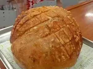 Una hogaza de pan crujiente, de color marrón dorado, con un patrón de cortes en forma de cuadrícula en la parte superior