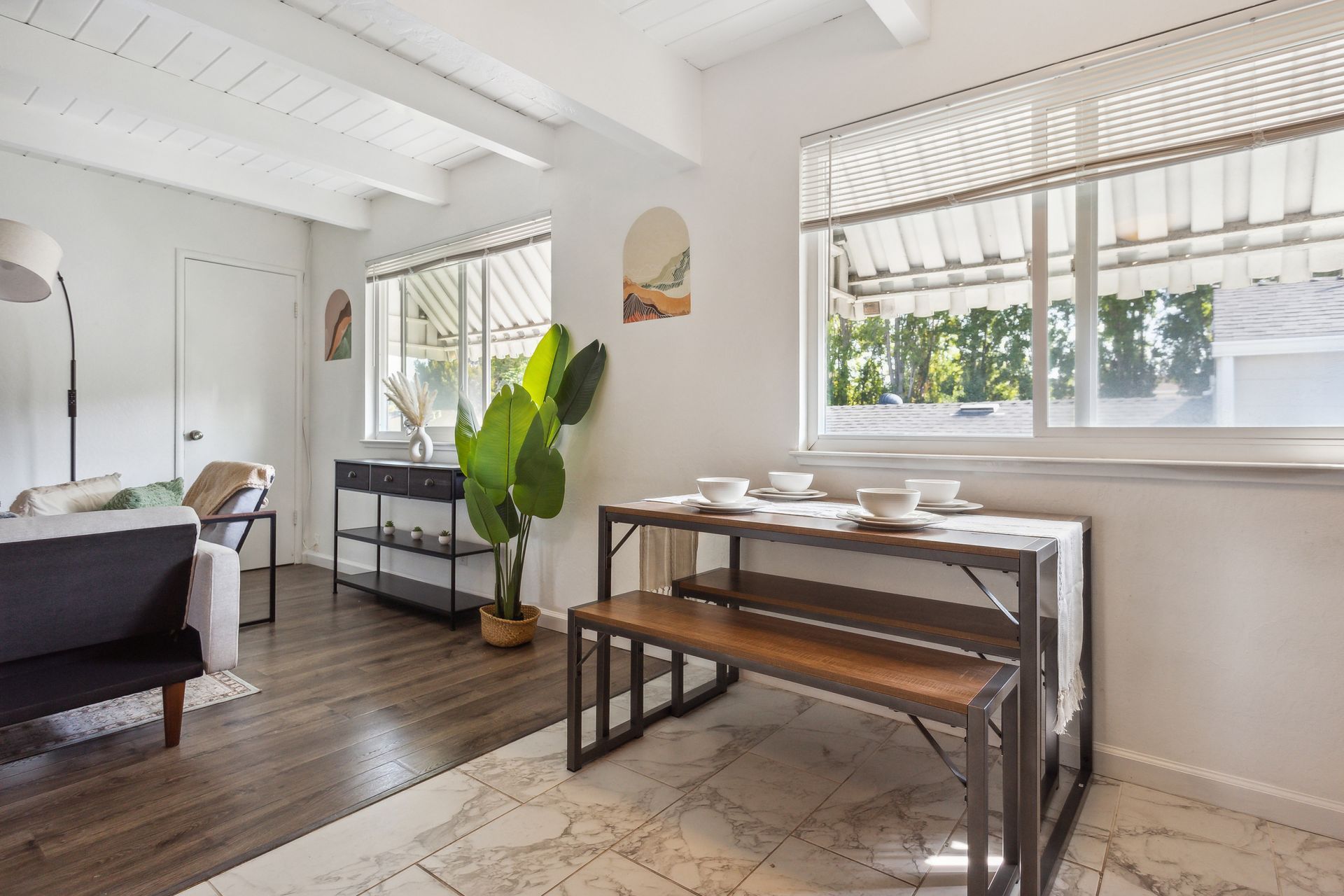 A living room with a table and a bench in front of a window.