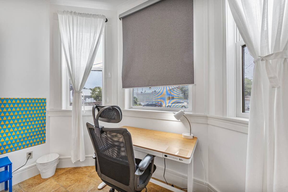 A room with a desk and chair in front of a window.