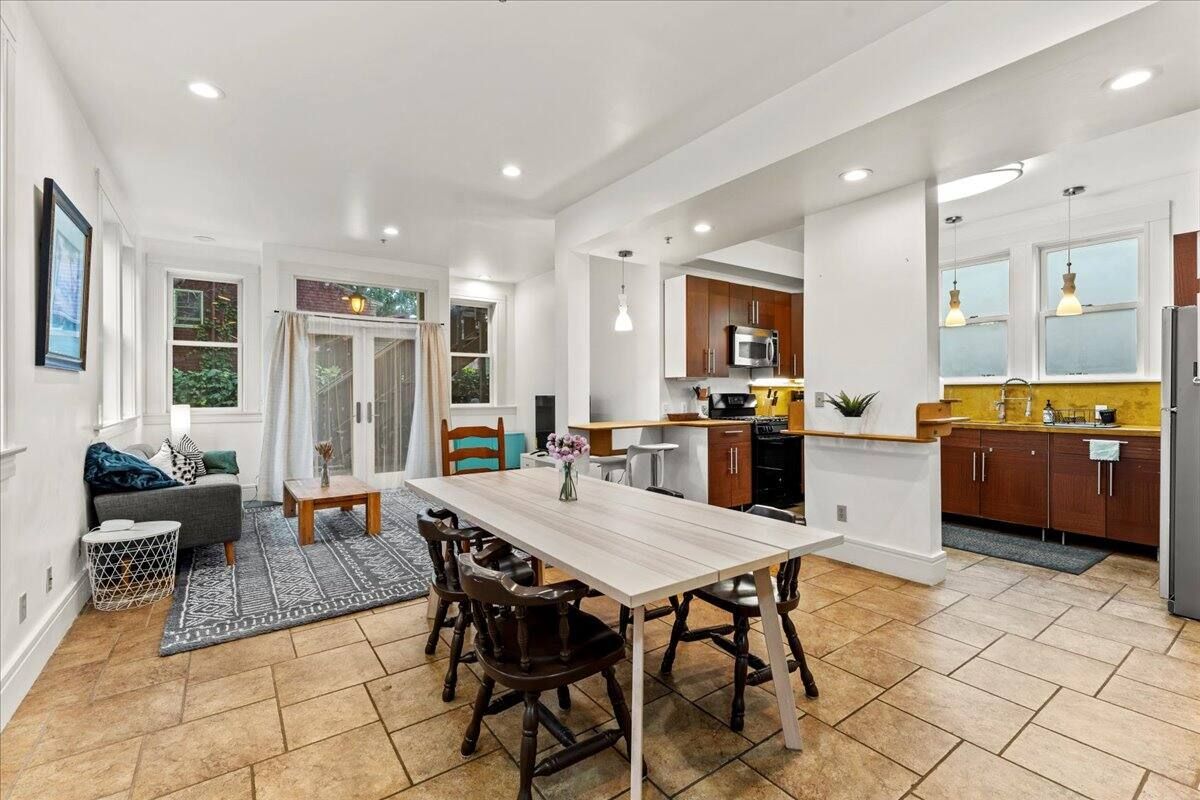 A living room with a dining table and chairs and a kitchen.