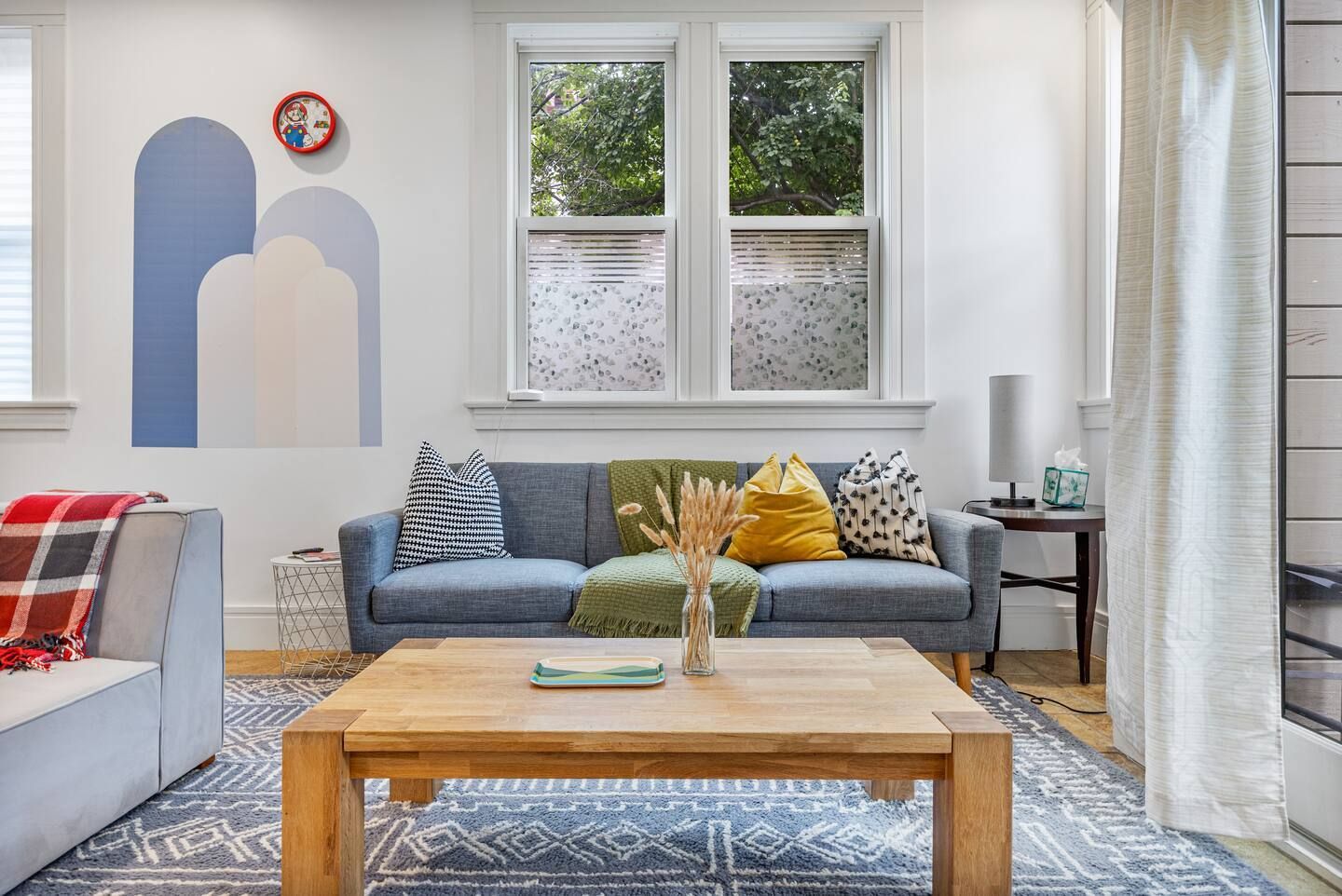 A living room with a couch , coffee table , and two windows.