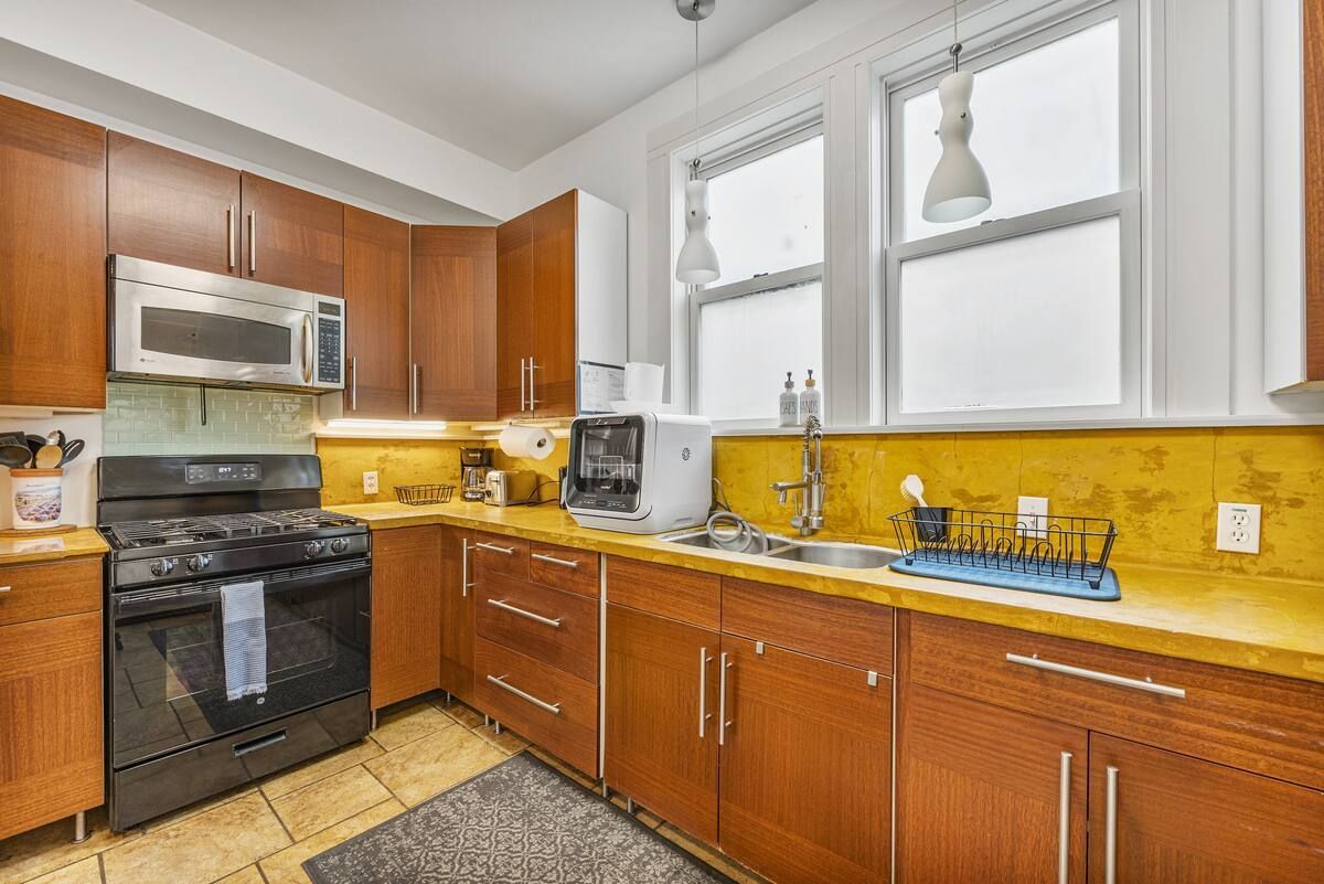 A kitchen with wooden cabinets , stainless steel appliances , a stove and a sink.