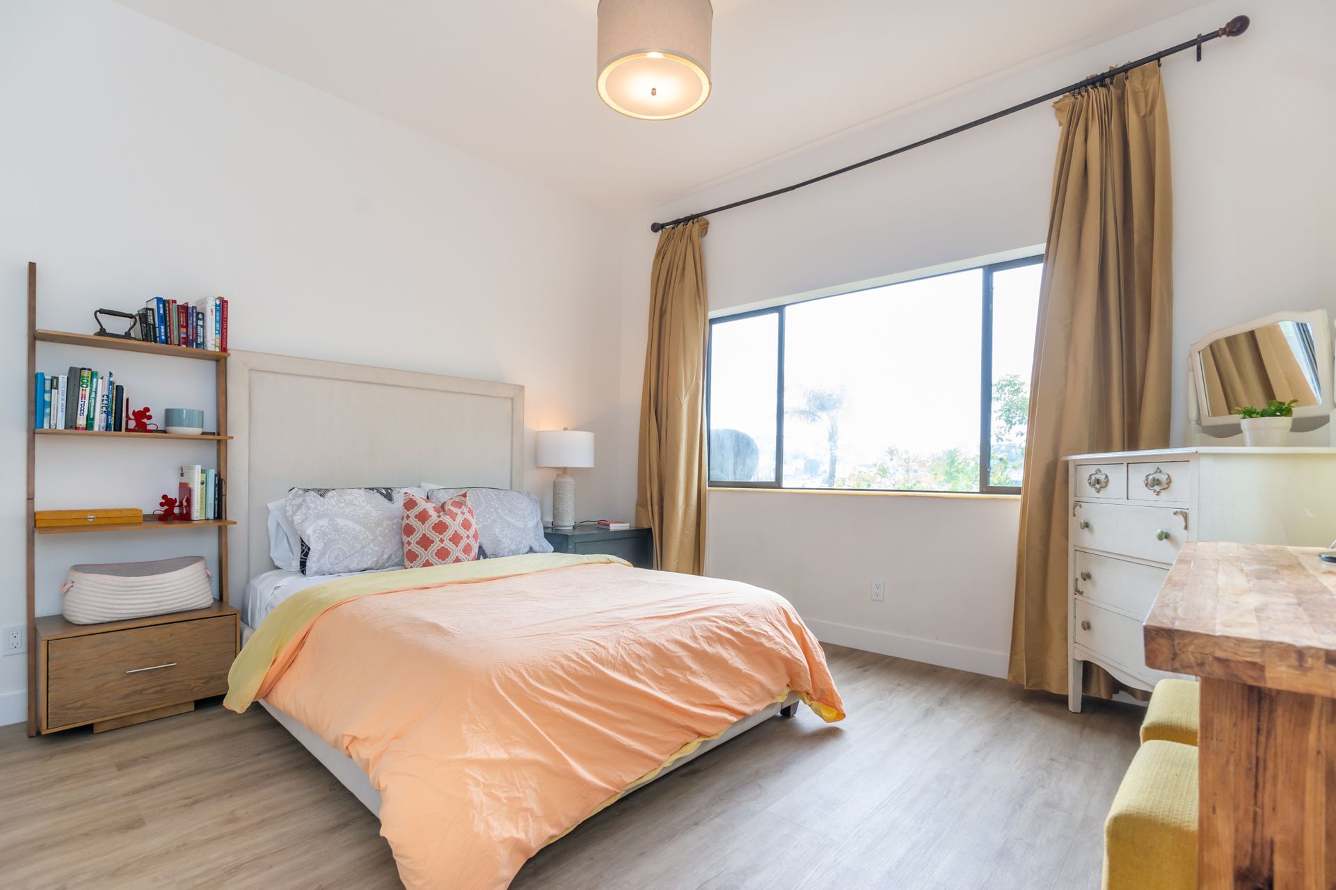 A bedroom with a bed , dresser , bookshelf and window.
