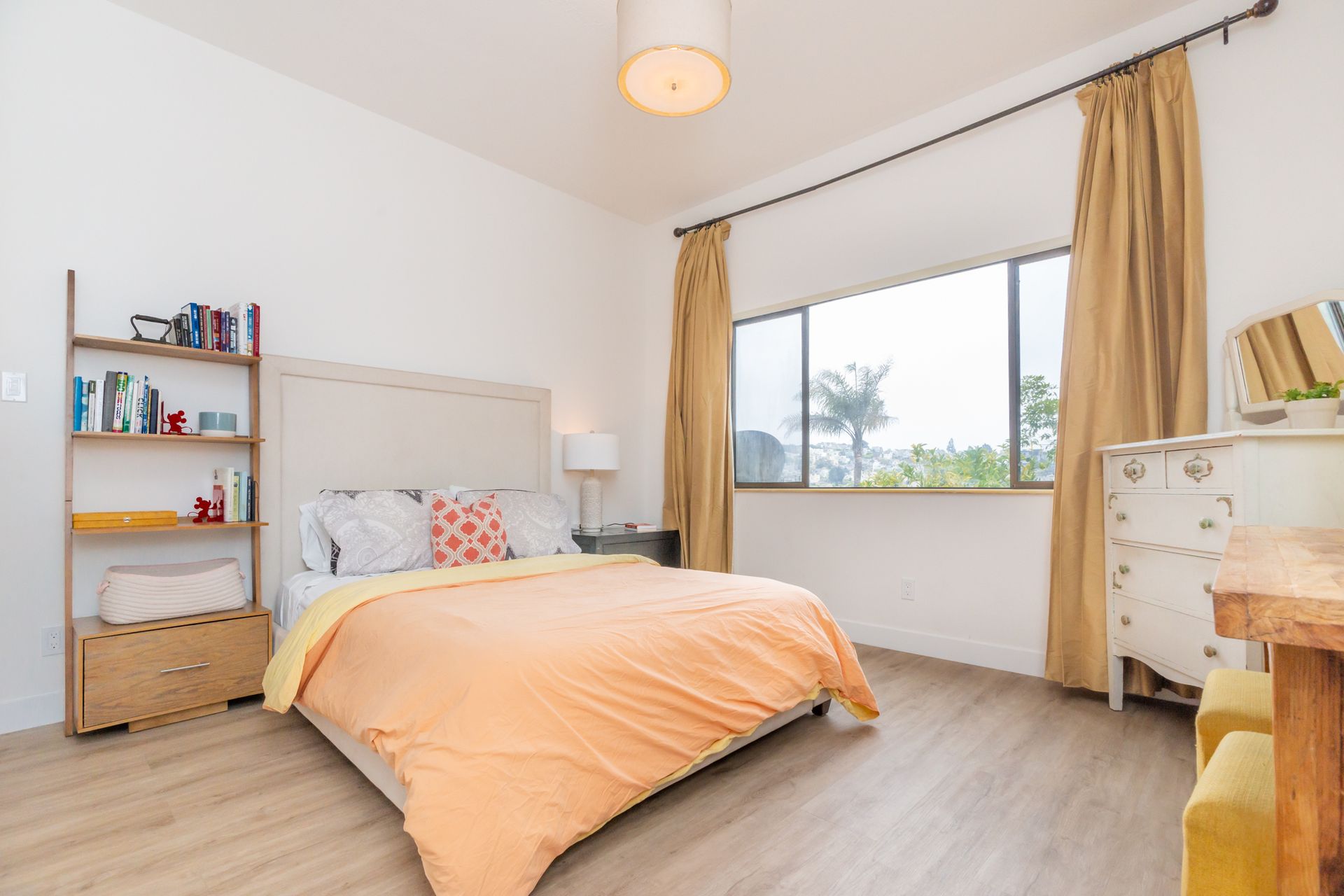 A bedroom with a bed , dresser , bookshelf and window.