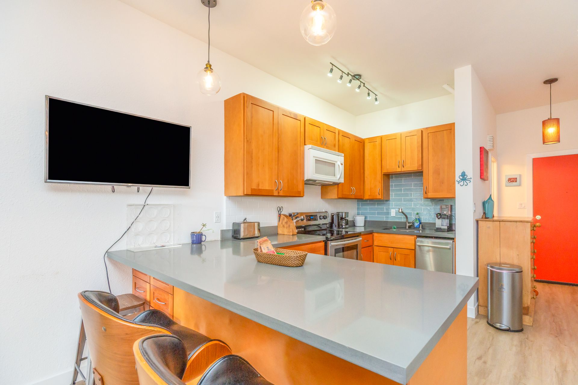 A kitchen with orange cabinets and a flat screen tv on the wall.