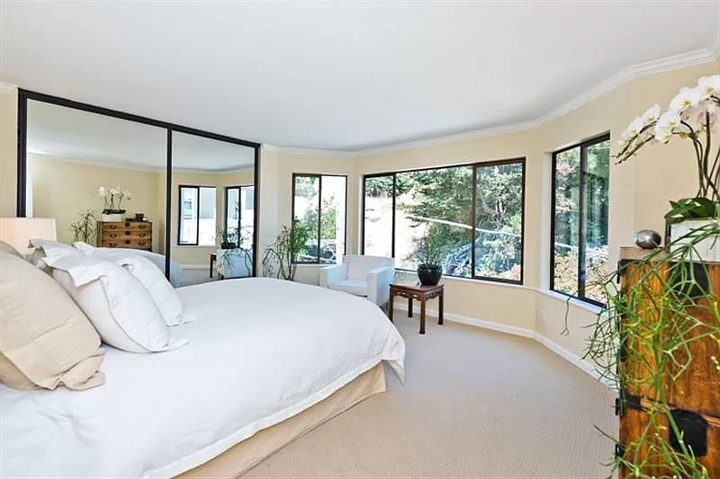 A bedroom with a large bed and lots of windows