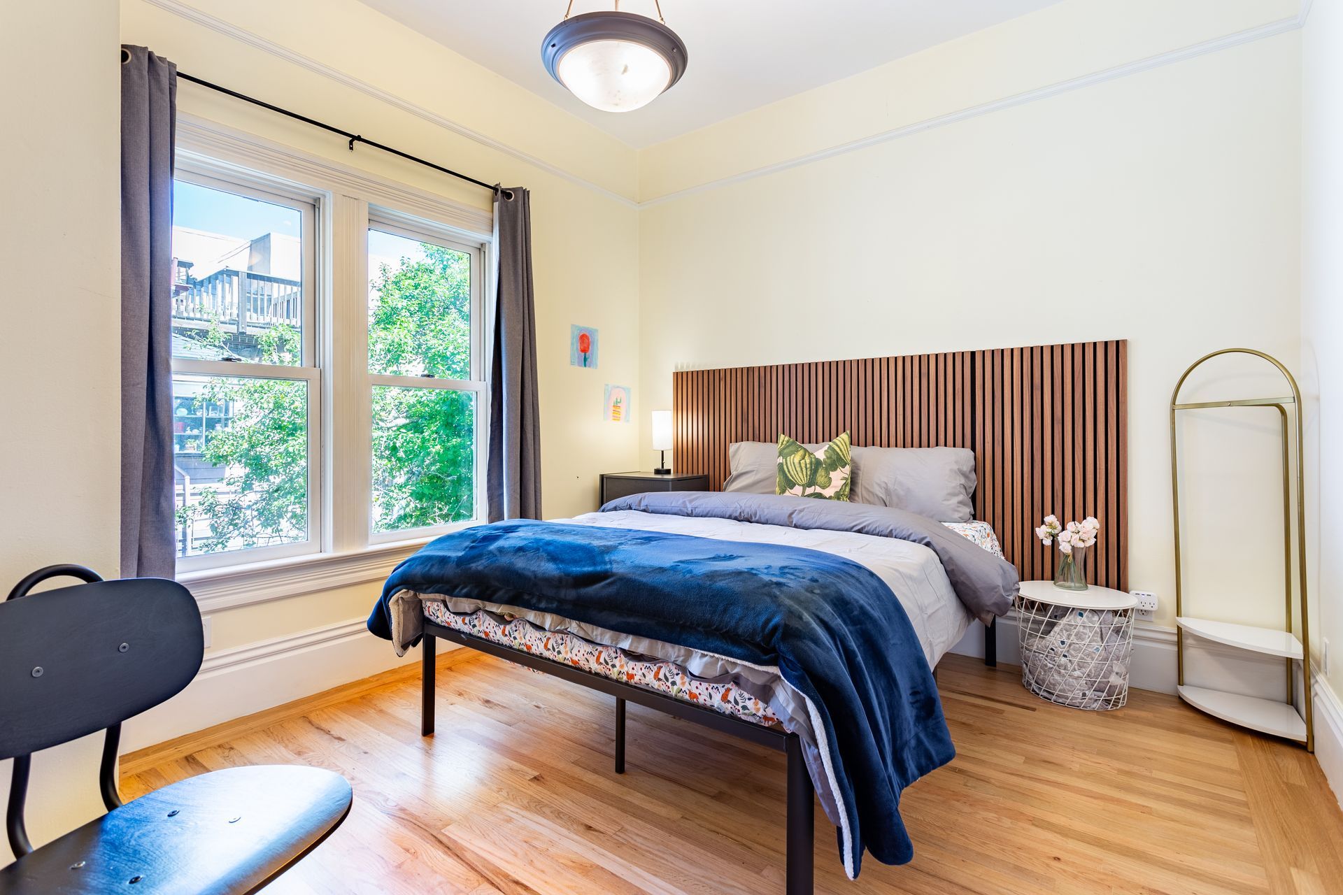 A bedroom with a bed , two windows , a chair and a mirror.