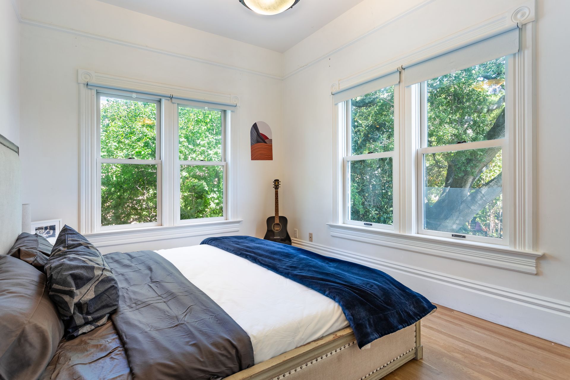 A bedroom with a large bed and a guitar in the corner.