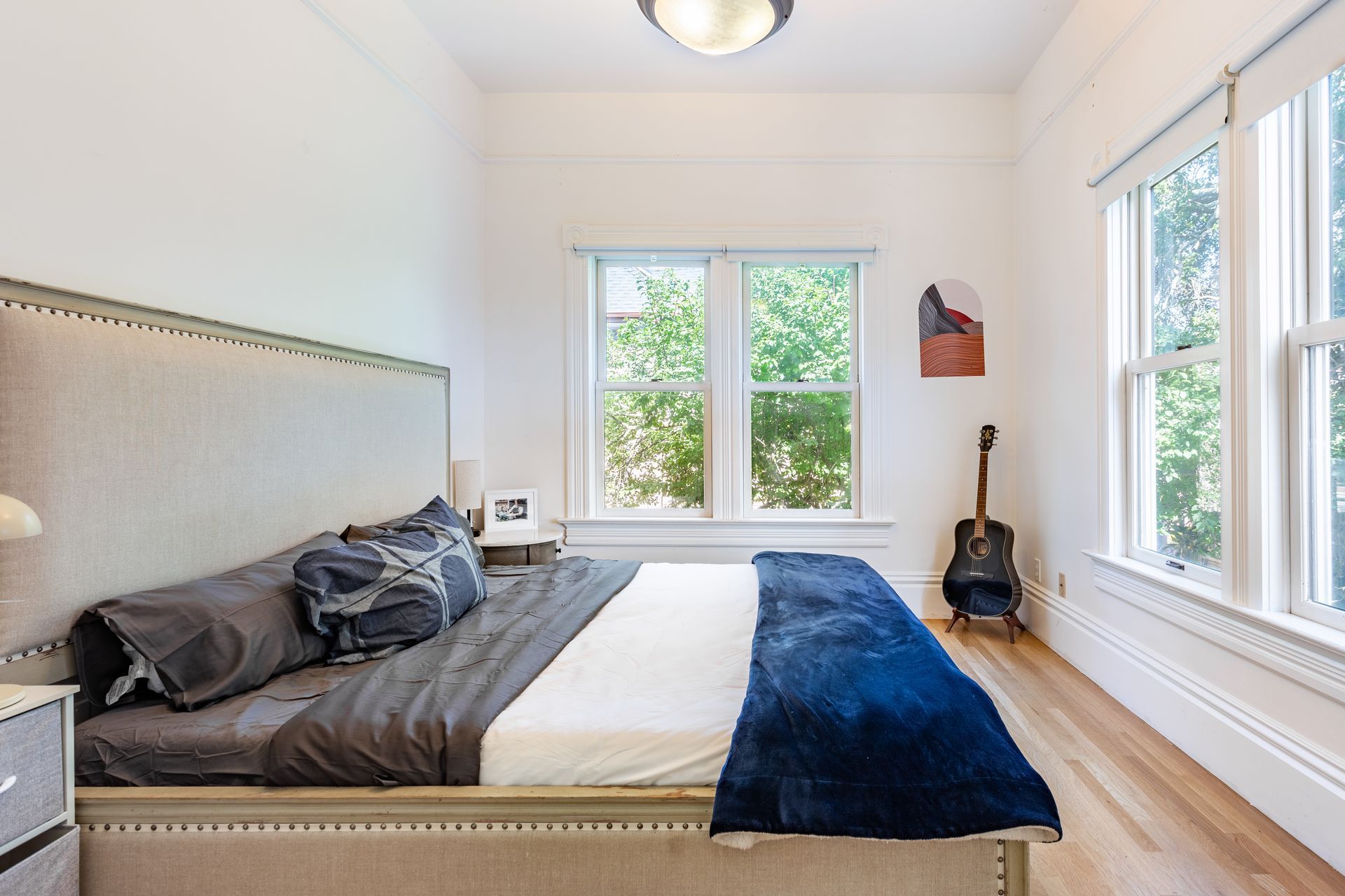 A bedroom with a large bed and a guitar on the wall.