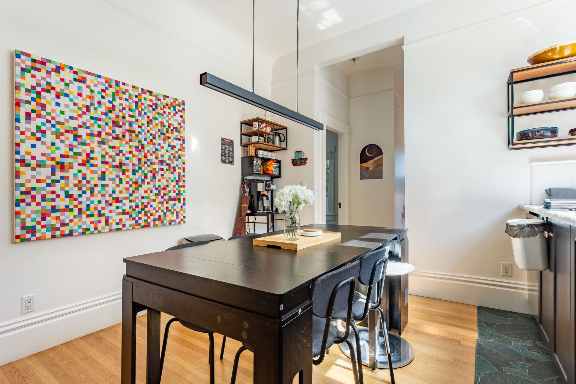 A dining room with a table and chairs and a painting on the wall.