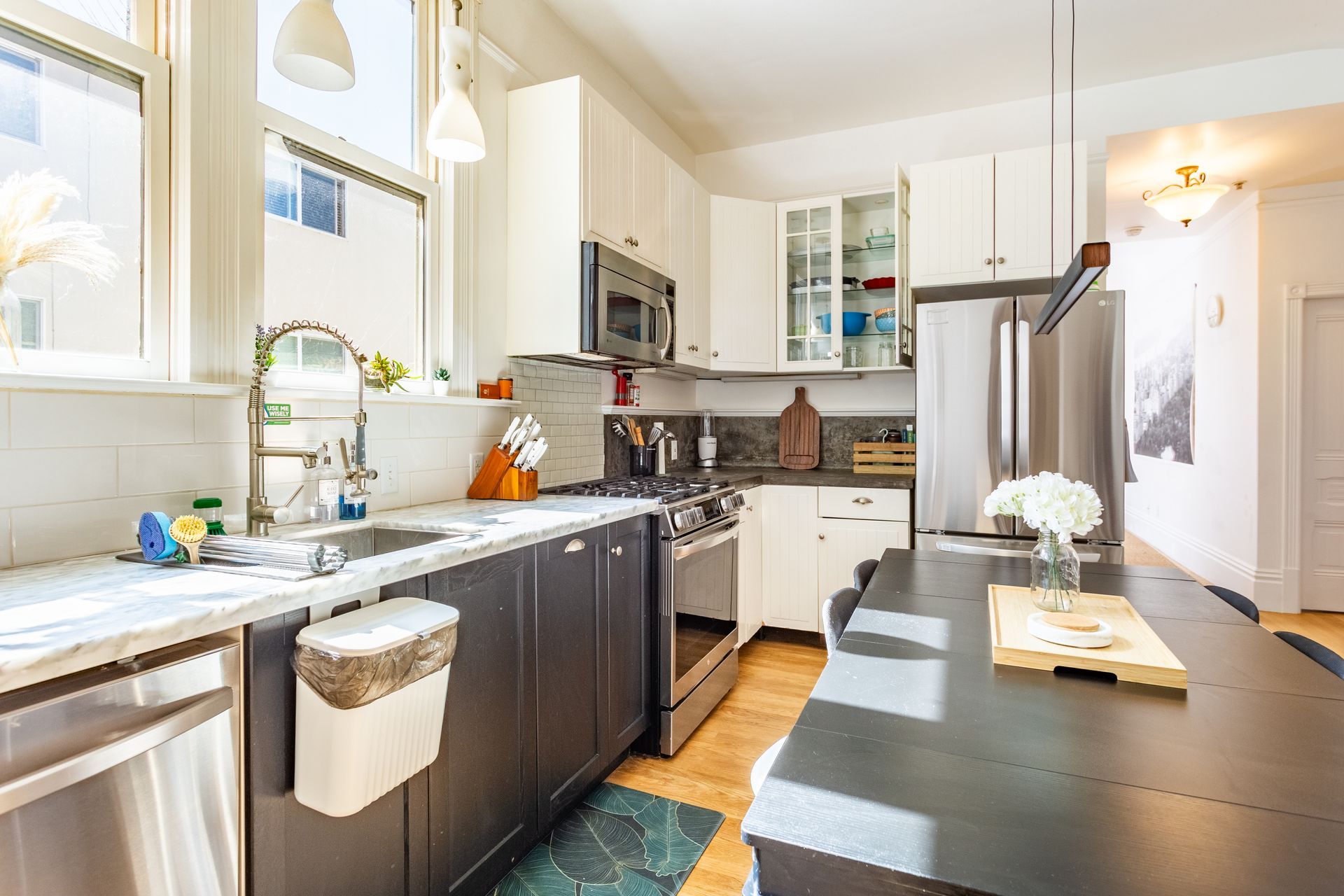 A kitchen with stainless steel appliances , white cabinets , a sink , and a refrigerator.