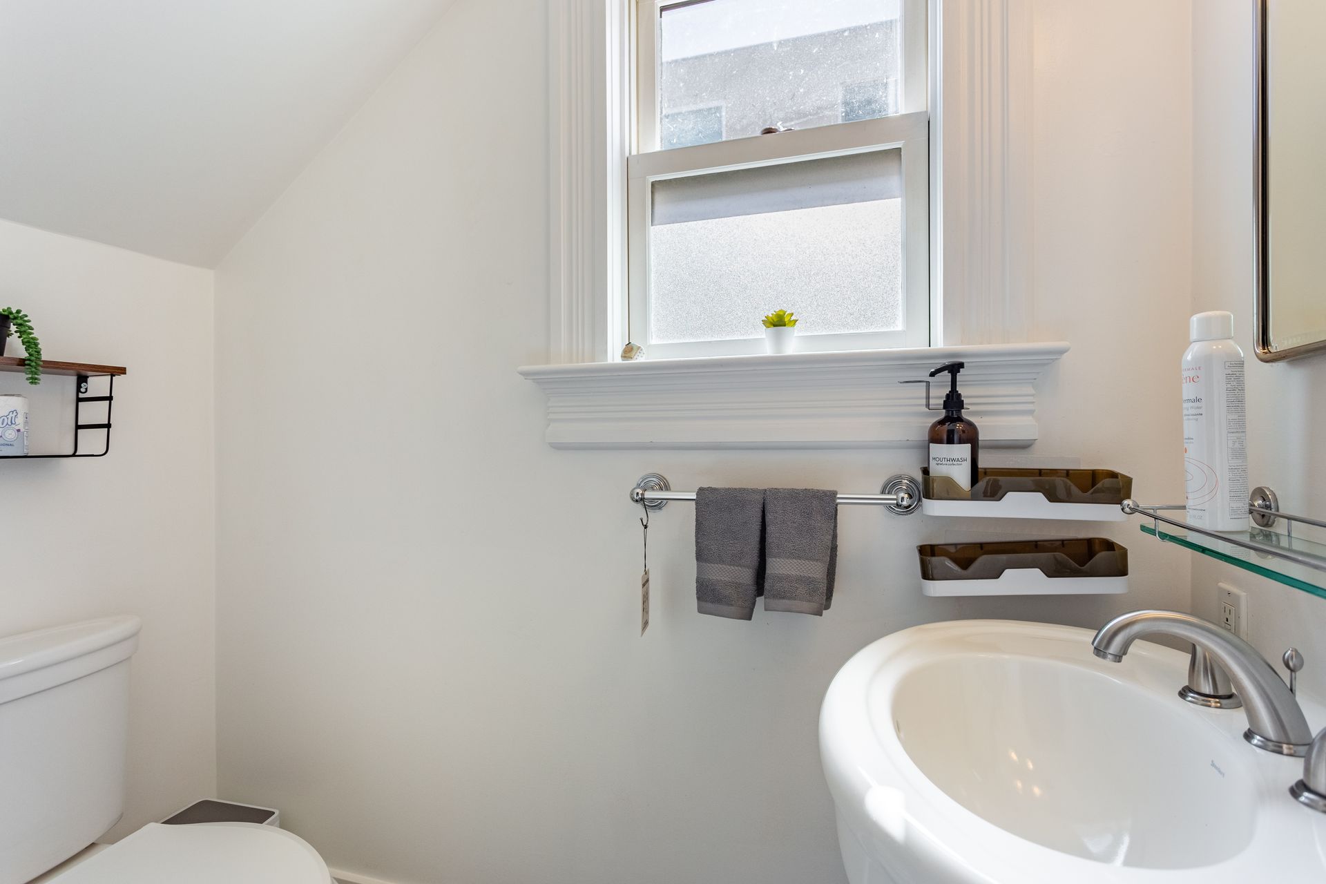 A bathroom with a sink , toilet and window.