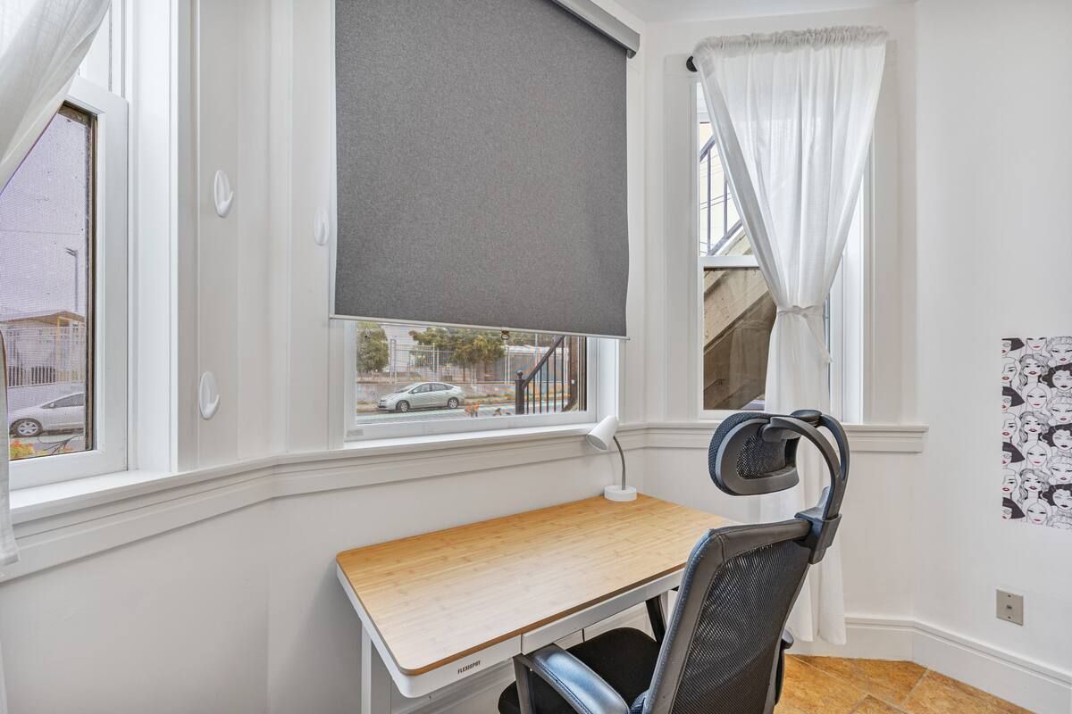 A room with a desk and chair in front of a window.