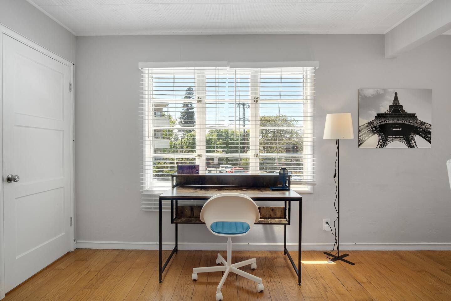 A room with a desk and chair in front of a window.