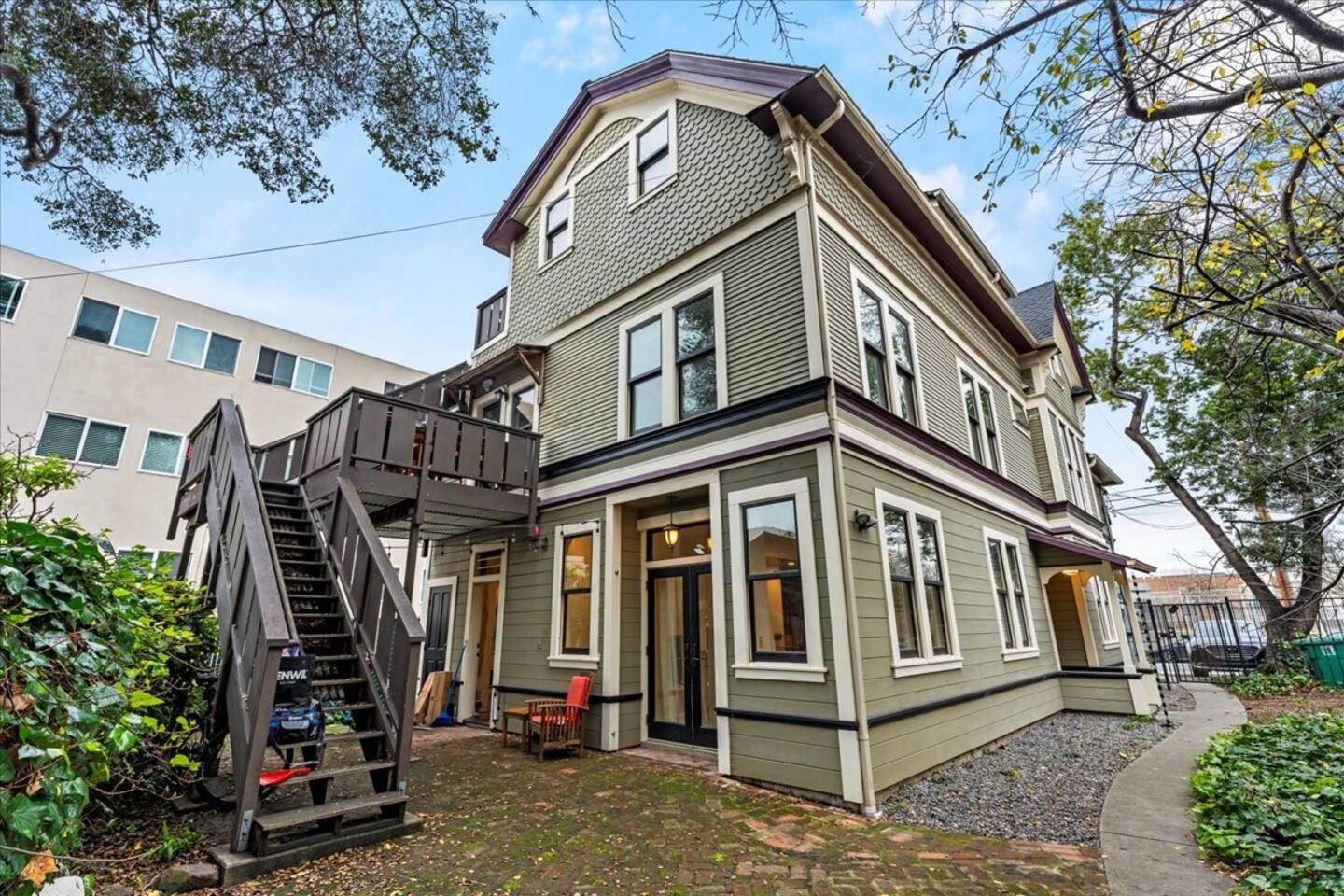 A large green house with stairs leading up to the second floor.