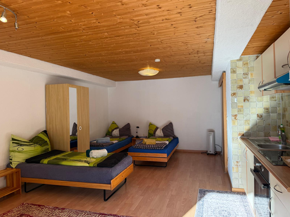 Das Gebäude der Pizzeria Hotel Posta vor einem schneebedeckten Berg im Hintergrund. Weisses Gebäude mit schwarzer Schrift.