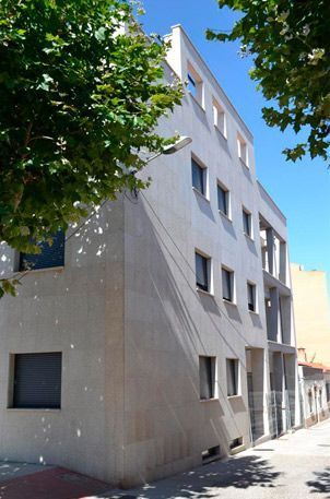 Un edificio con muchas ventanas y un árbol delante.