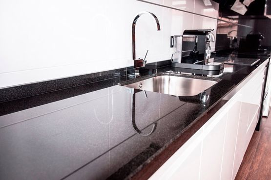 Una cocina con encimera negra y fregadero de acero inoxidable.