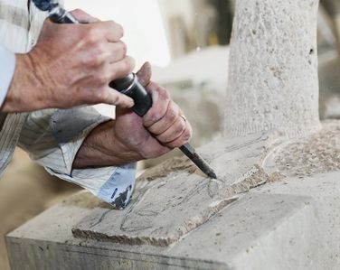 Un hombre está tallando una escultura de piedra con un martillo.