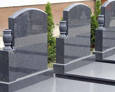 Una hilera de lápidas con jarrones en un cementerio.