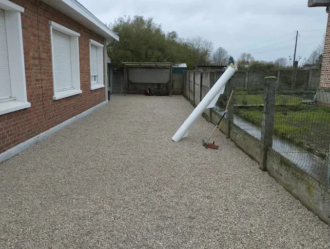 Une maison en briques avec une allée de gravier devant elle