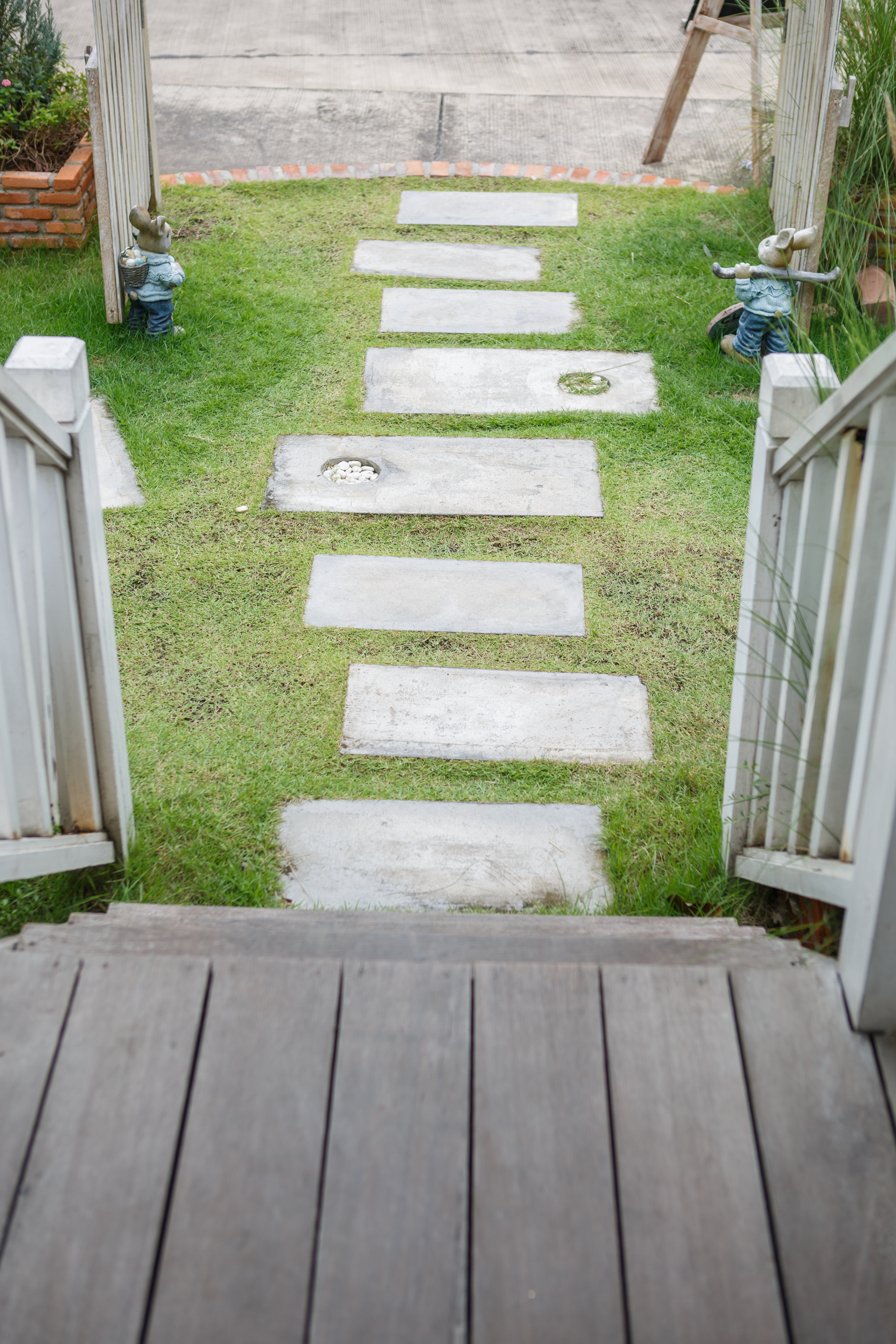 Une terrasse en bois avec des marches menant à un chemin herbeux.