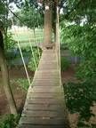 Eine Holzbrücke zwischen zwei Bäumen im Wald.