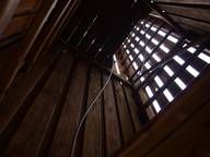 Blicken nach oben auf eine Holztreppe, durch deren Fenster Licht scheint.