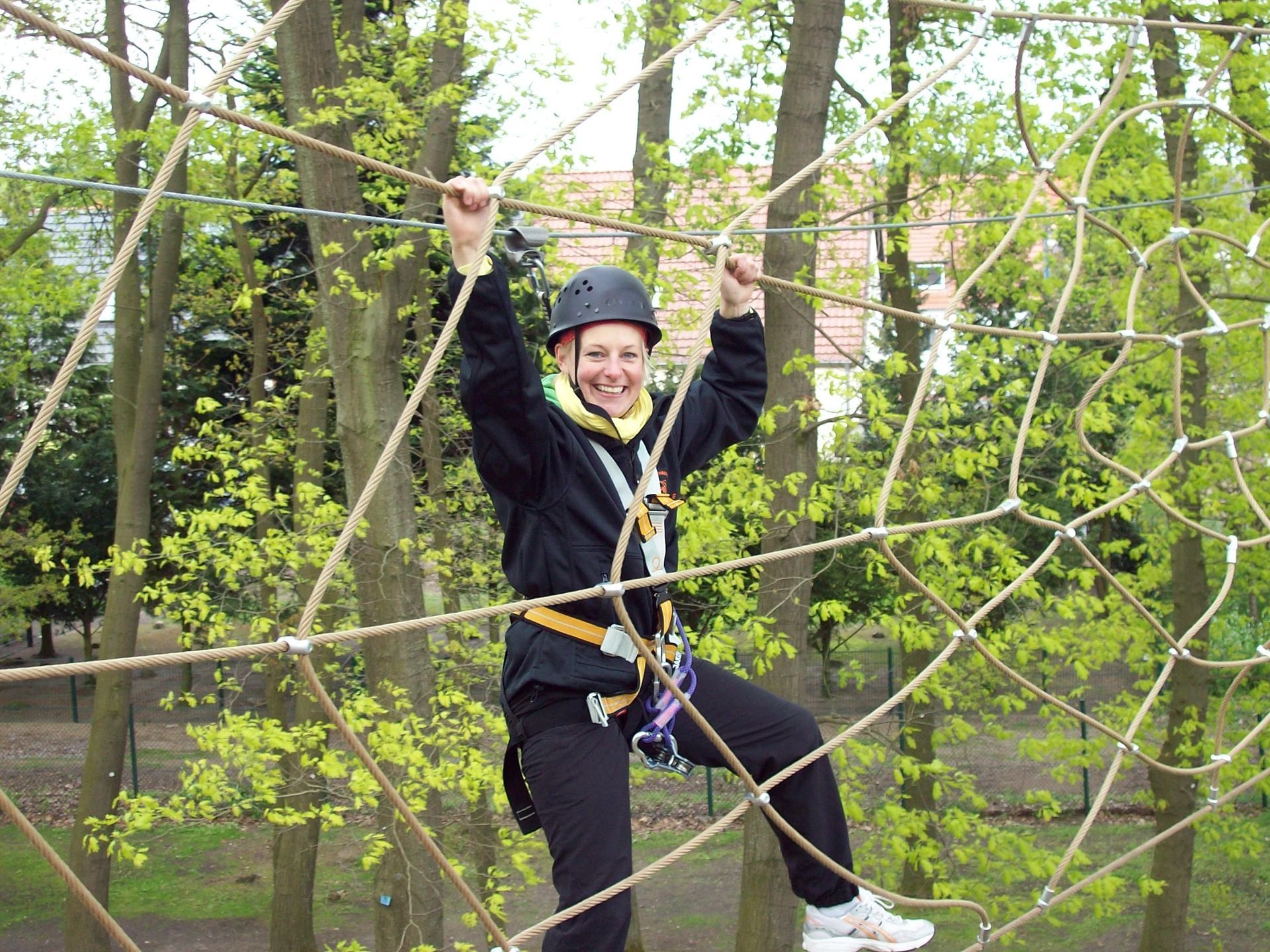 Eine Frau klettert einen Hochseilgarten im Wald