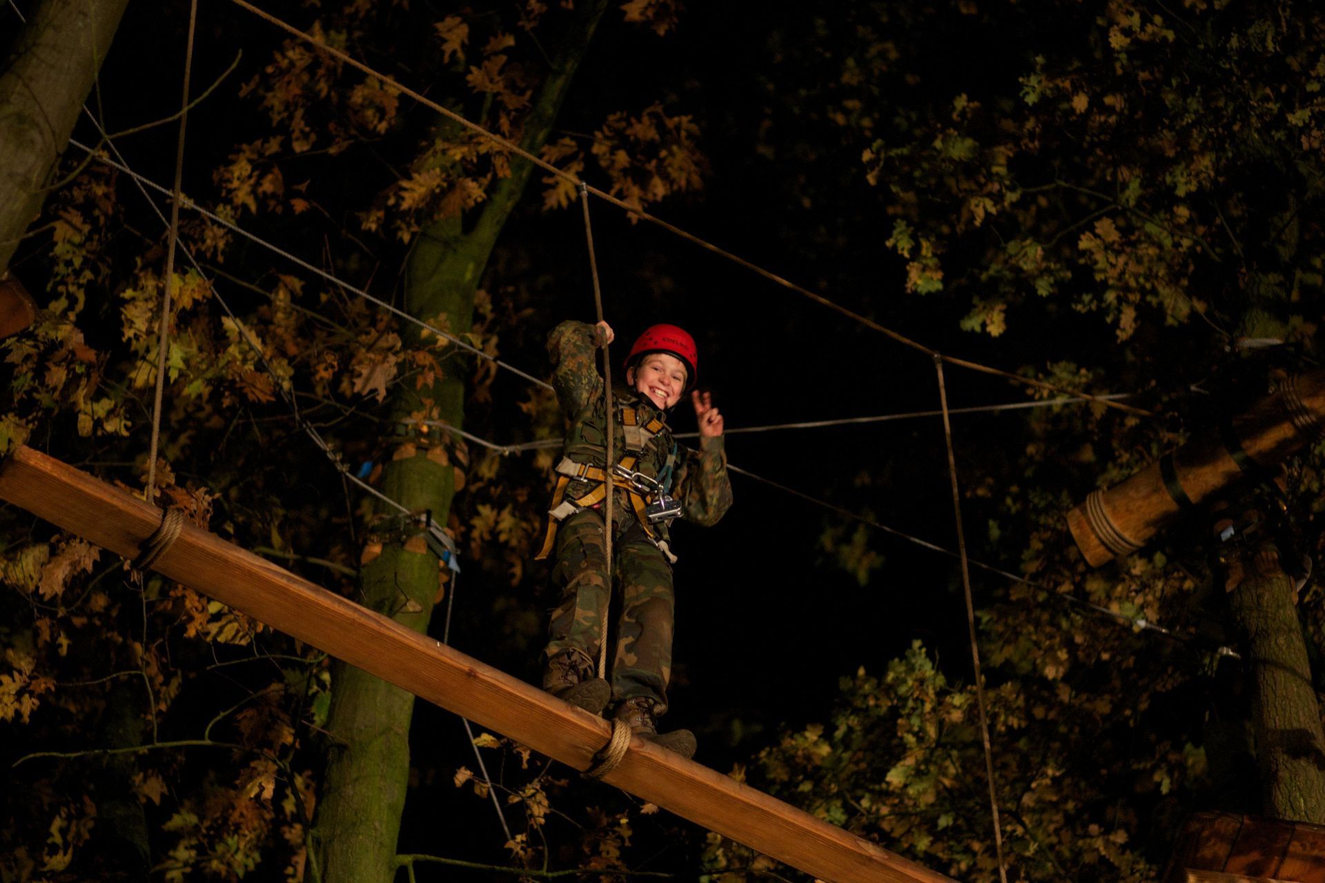 Eine Person steht nachts auf einem Hochseilgarten.