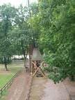 Eine Holzbrücke ist von Bäumen in einem Park umgeben.