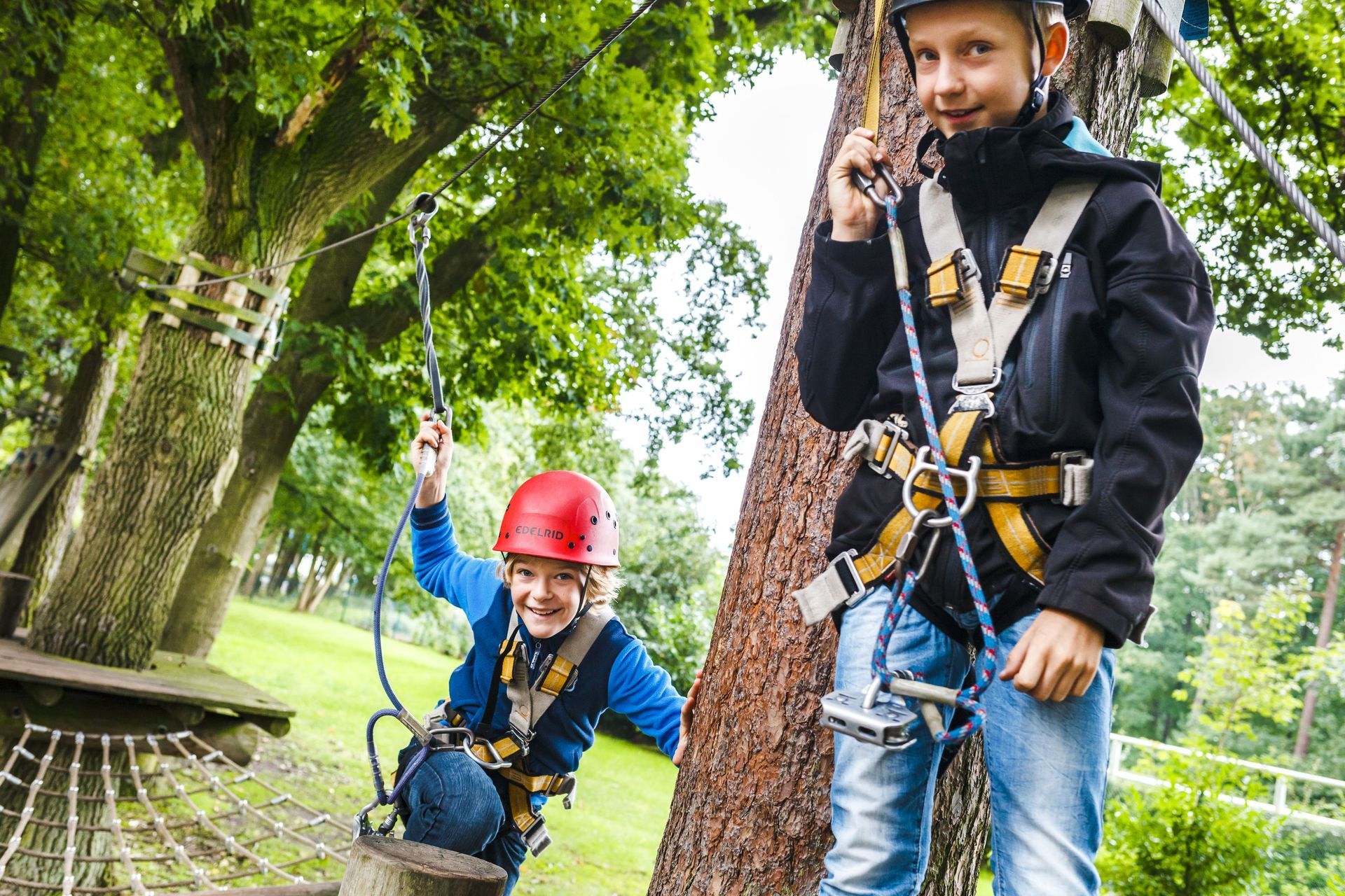 Zwei kleine Jungen stehen nebeneinander auf einem Hochseilgarten.