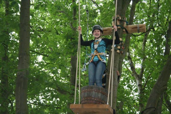 Eine Frau sitzt auf einer Holzplattform in einem Baum.