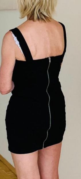 Der Rücken einer Frau, die ein schwarzes Kleid mit einem Reißverschluss auf der Rückseite trägt.