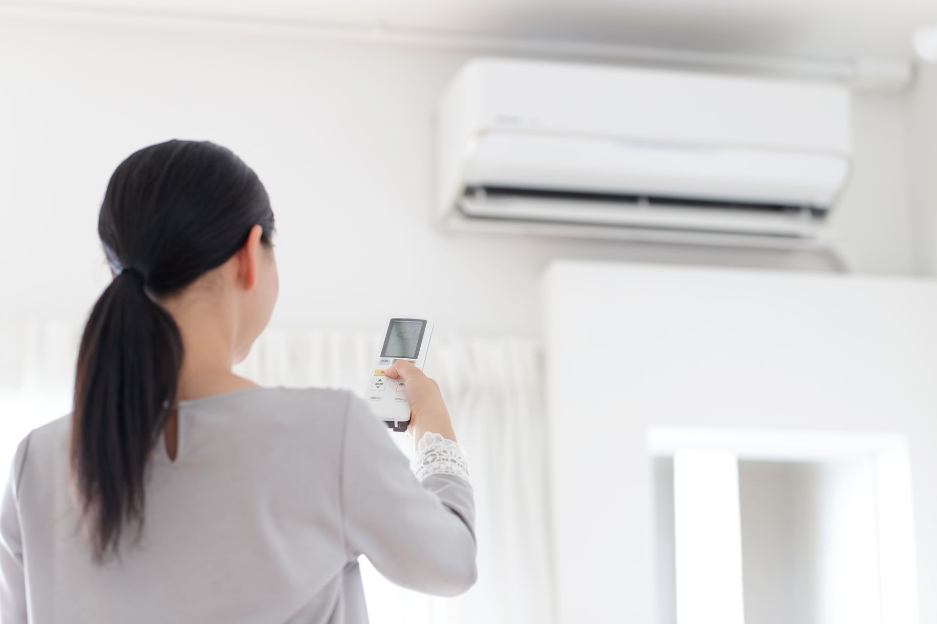 Une femme de dos devant une climatisation