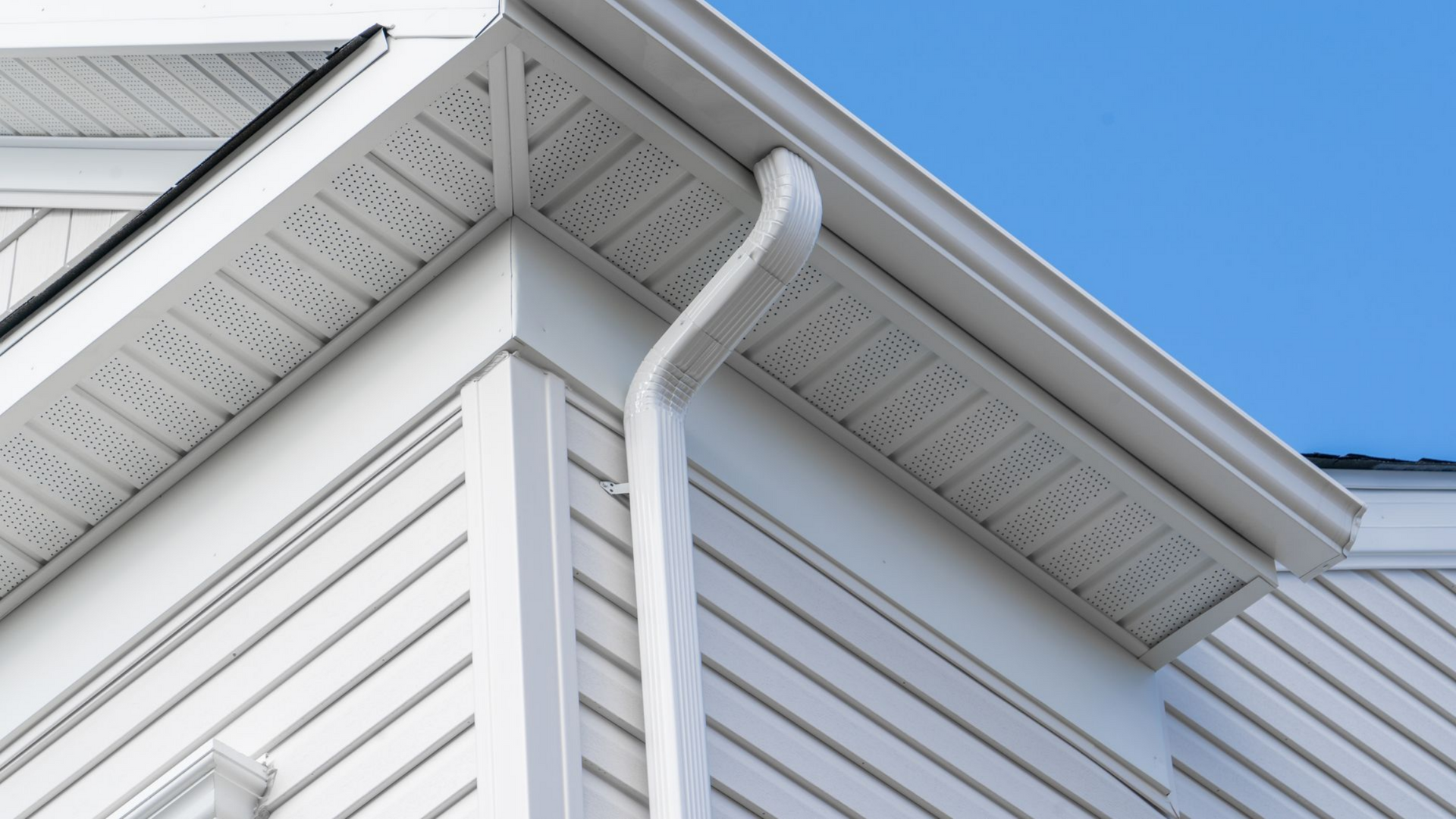 Une maison blanche avec gouttière et bardage.