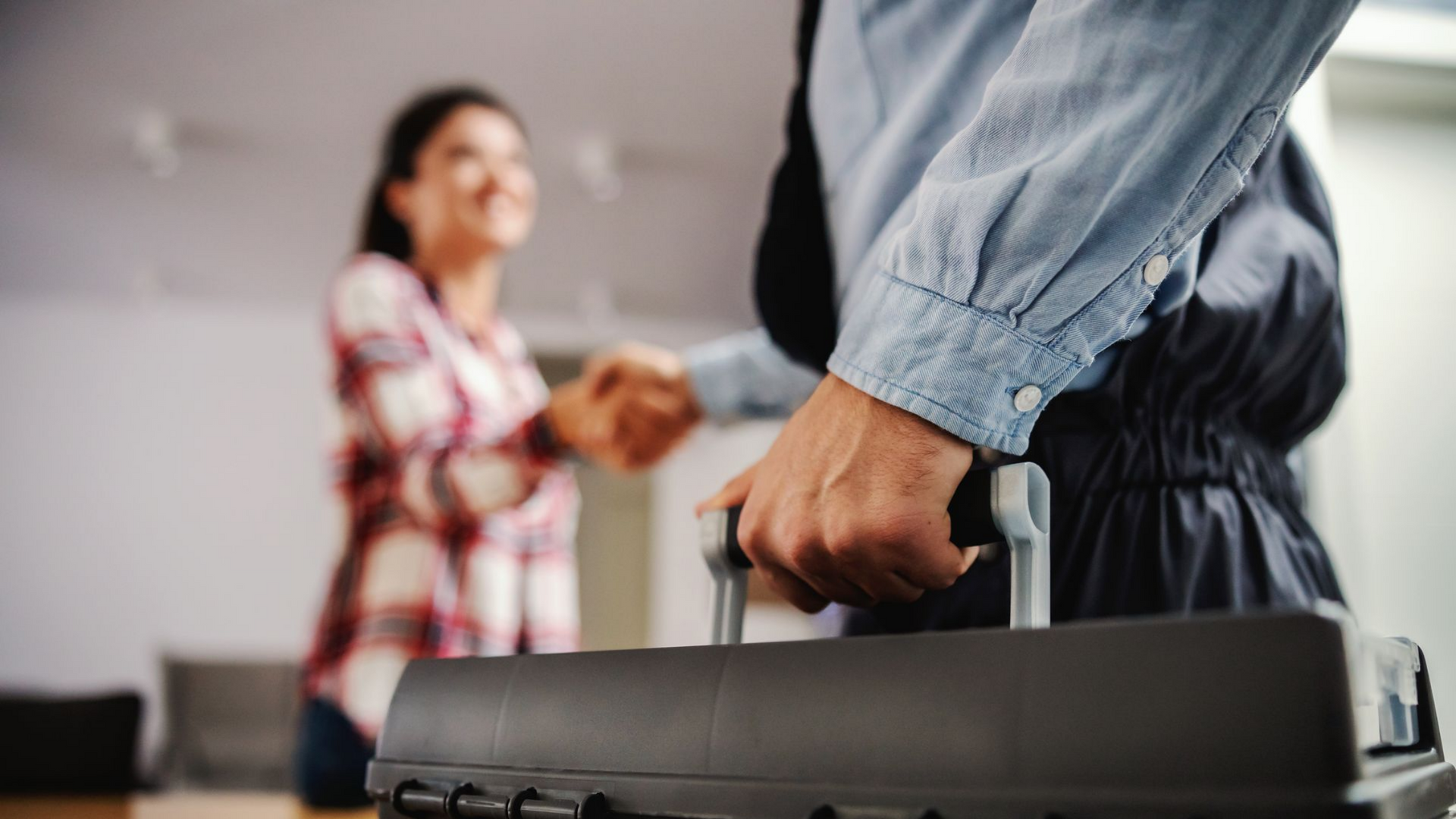 Un homme avec sa boîte à outils serre la main d'une femme à l'intérieur d'une maison.