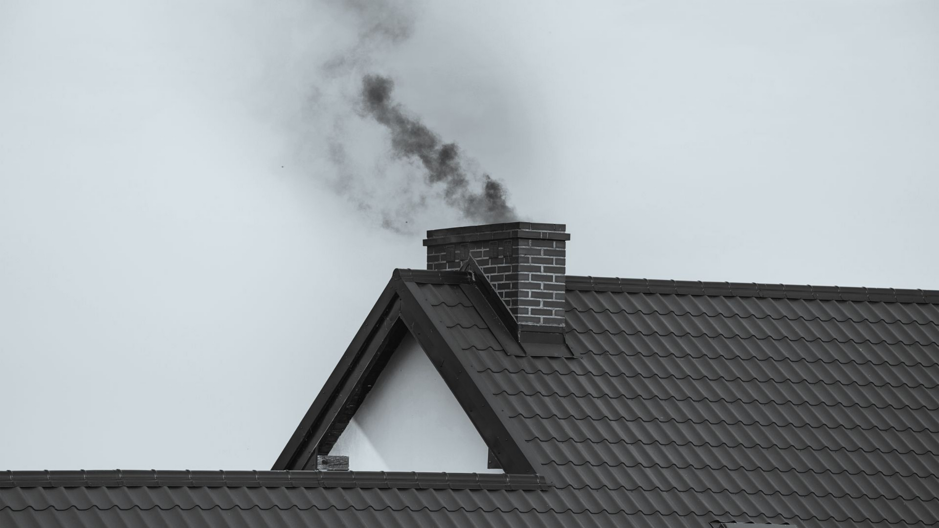 Cheminée d'une maison crachant une fumée noire.