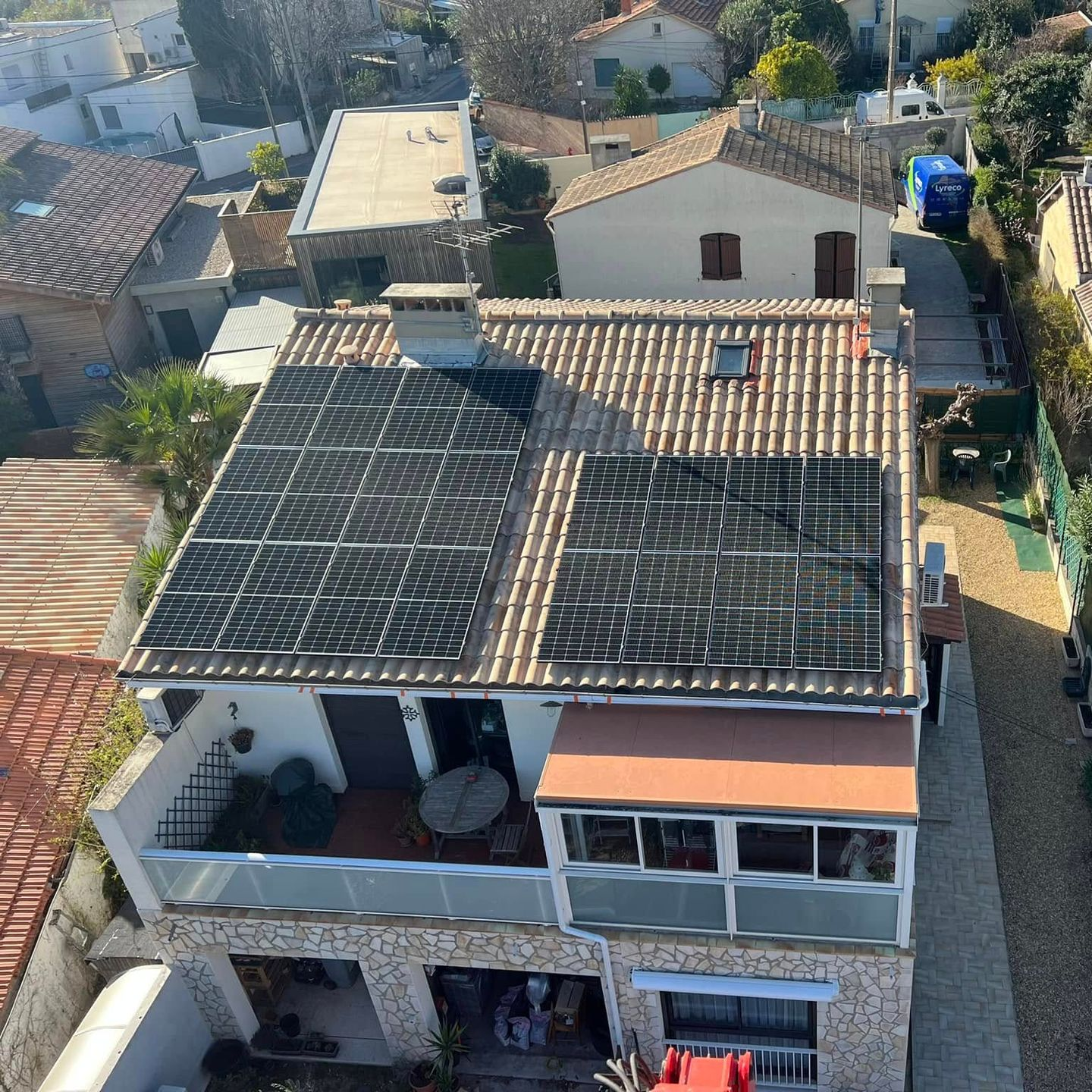 Vue aérienne d'une maison en pierre de deux étages avec des panneaux photovoltaïques sur son toit
