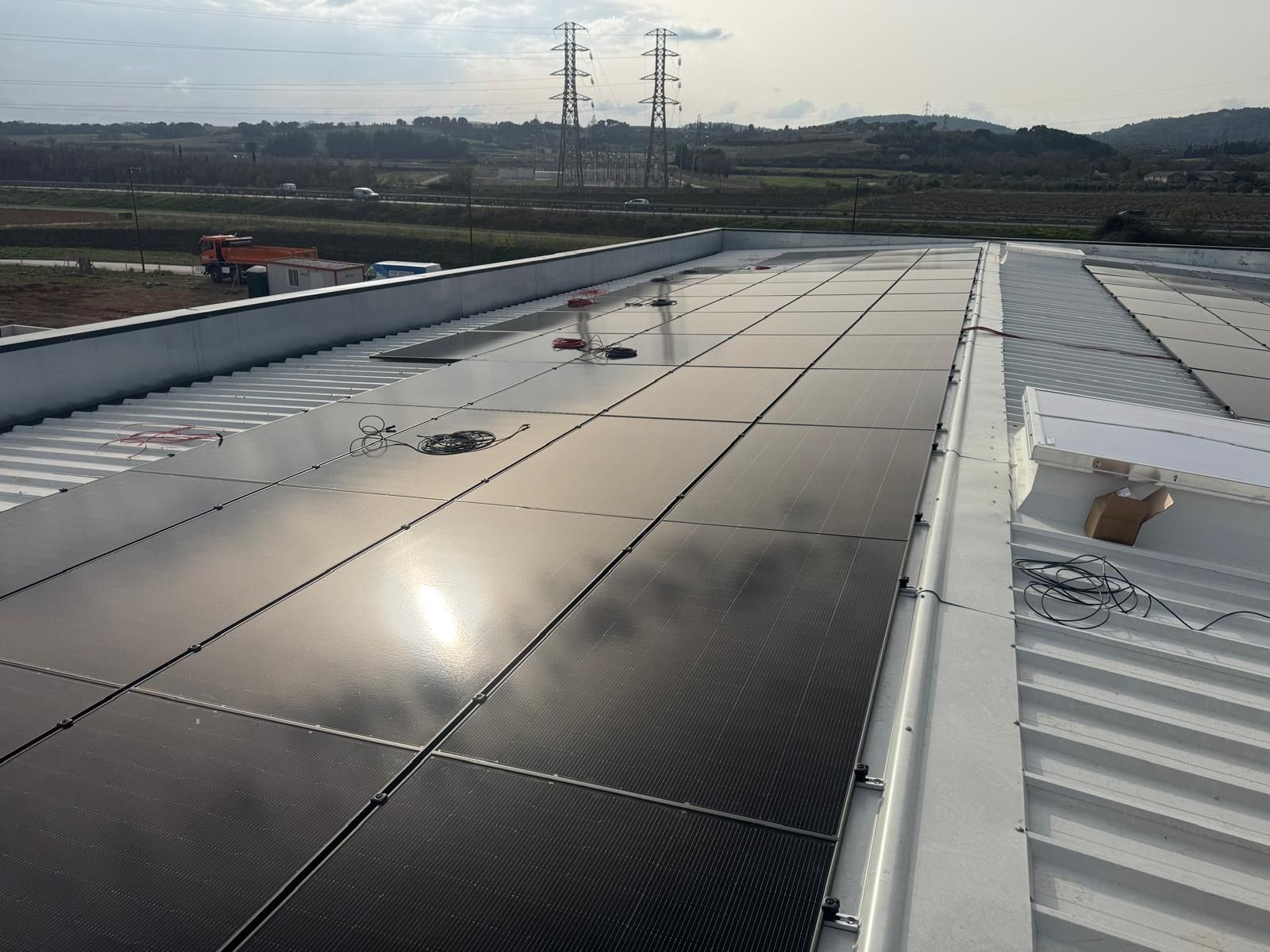 Des rangées de panneaux solaires sont installées sur un toit métallique industriel