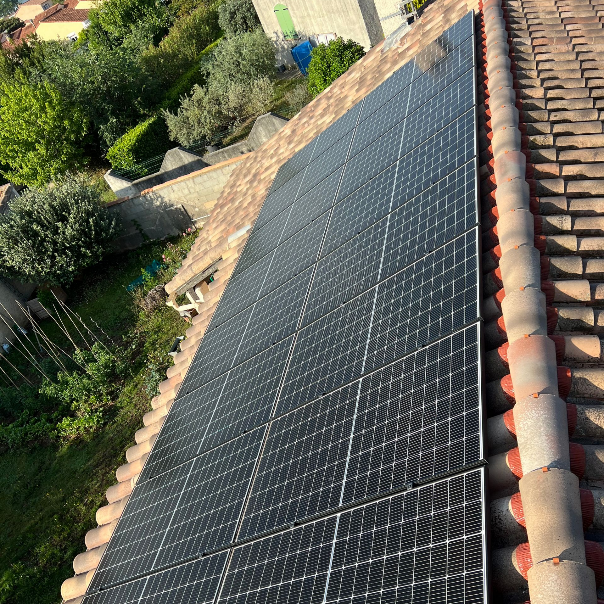Une longue rangée de panneaux photovoltaïques sombres, fixés sur un toit en tuiles