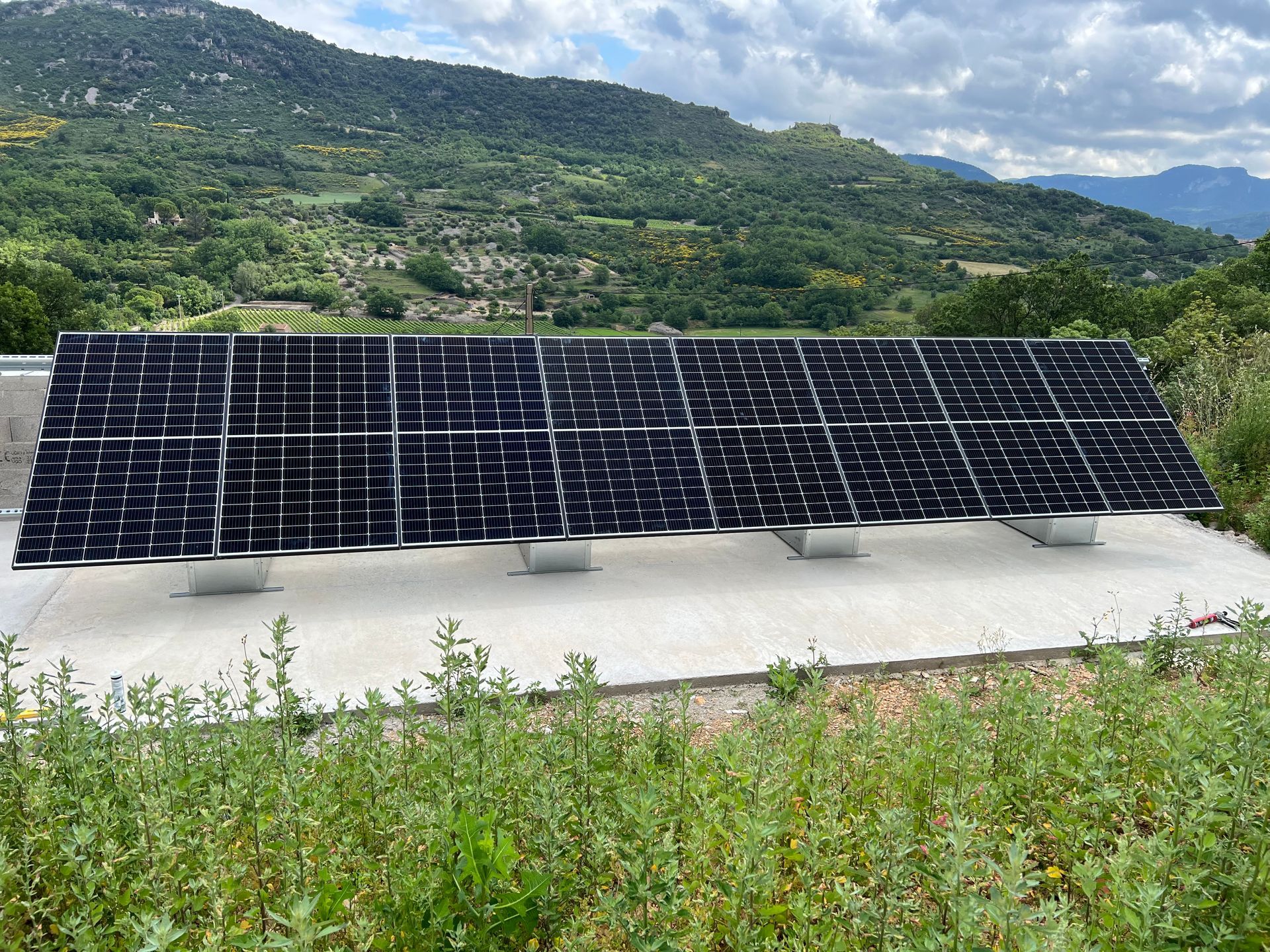 Longue rangée de panneaux photovoltaïques posés sur une surface en béton, vallée en arrière-plan