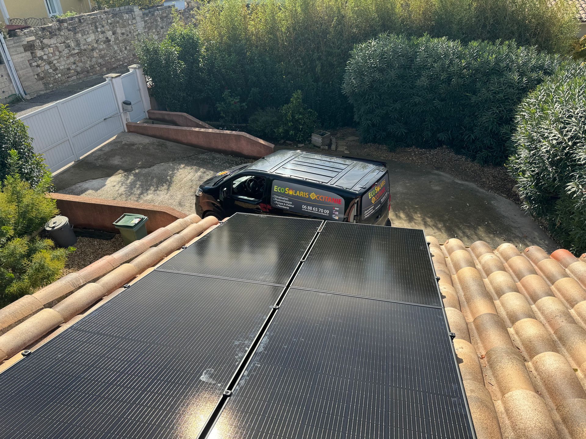 Panneaux photovoltaïques installés sur un toit en tuiles, camionnette de l'entreprise en contrebas