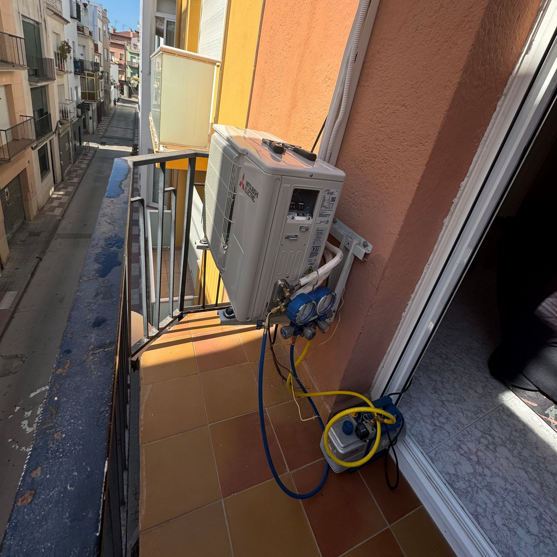 Maintenance d'un climatiseur installé sur un balcon et raccordé à une pompe à vide et à des manomètres