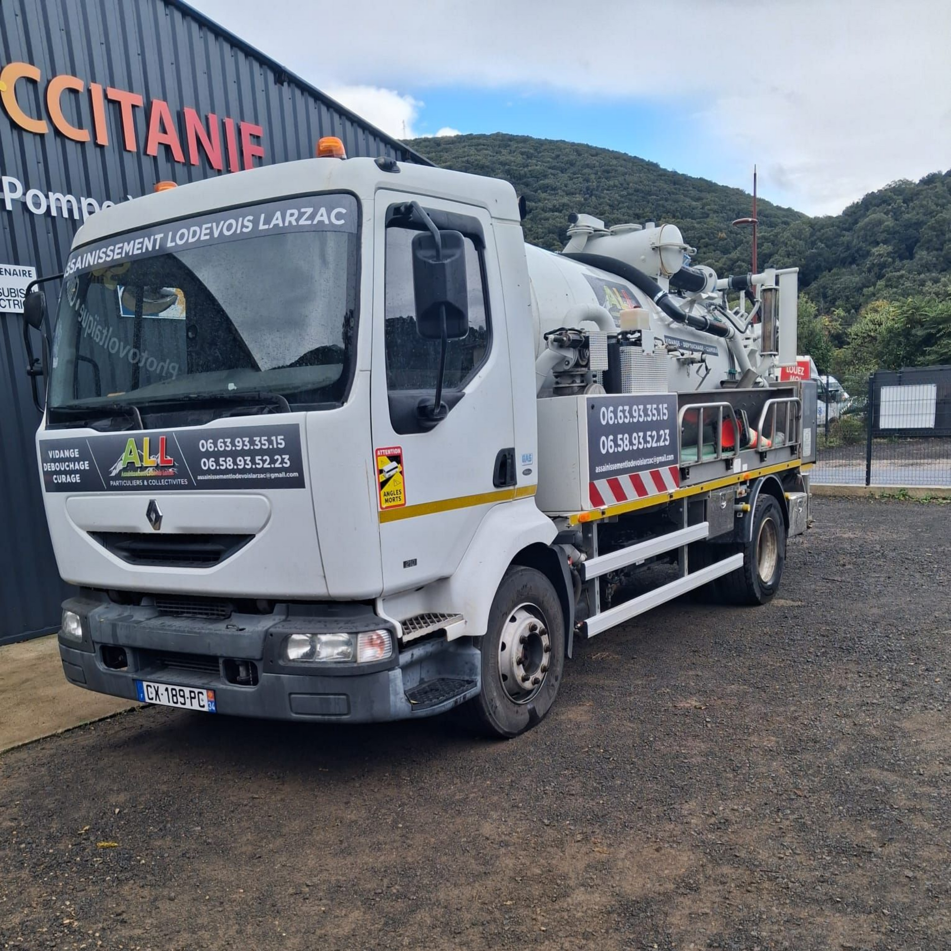 Camion blanc garé à l'extérieur, devant un bâtiment gris